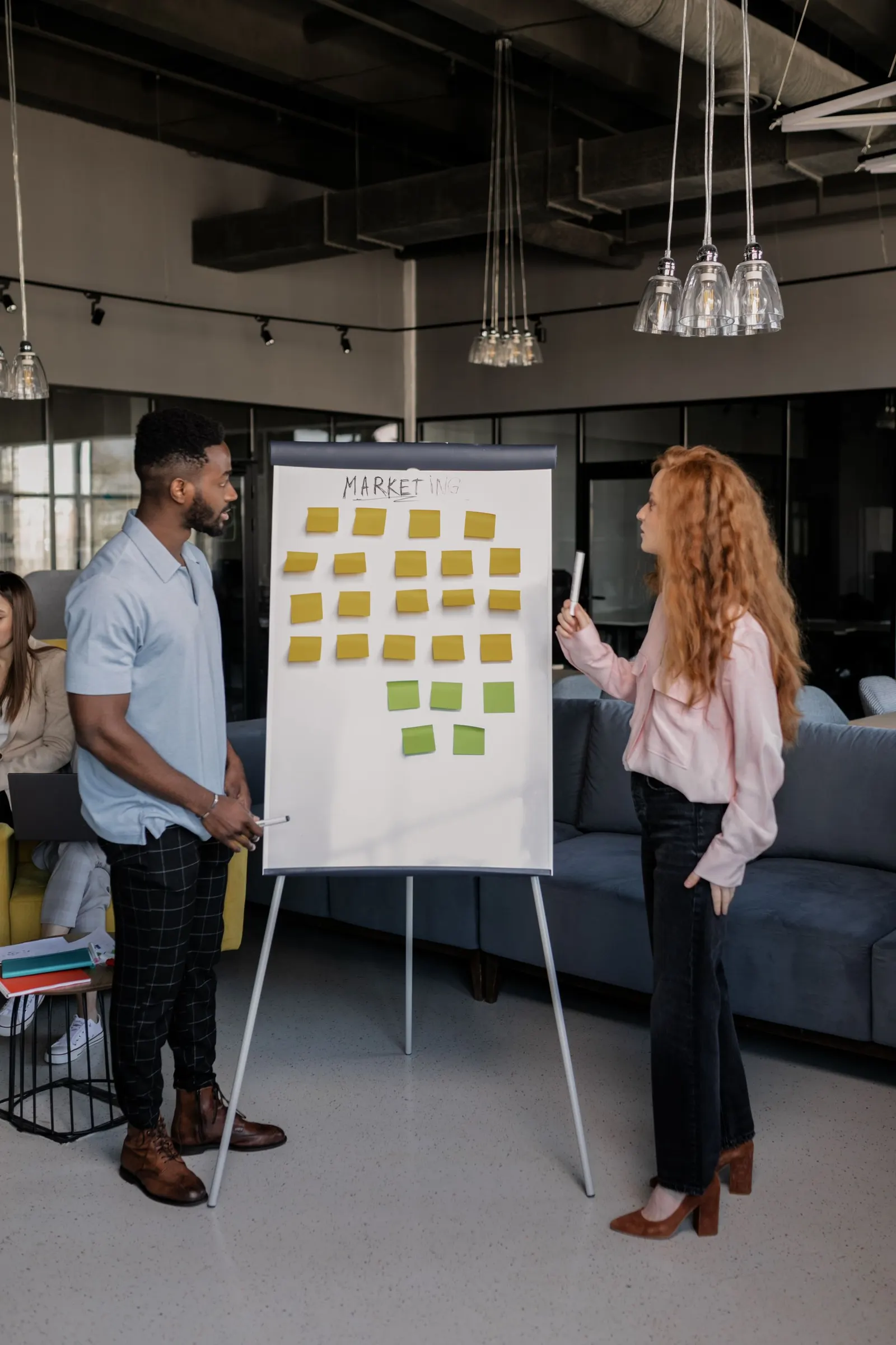 Zwei Personen planen Marketing-Inhalte an einem Flipchart mit Haftnotizen