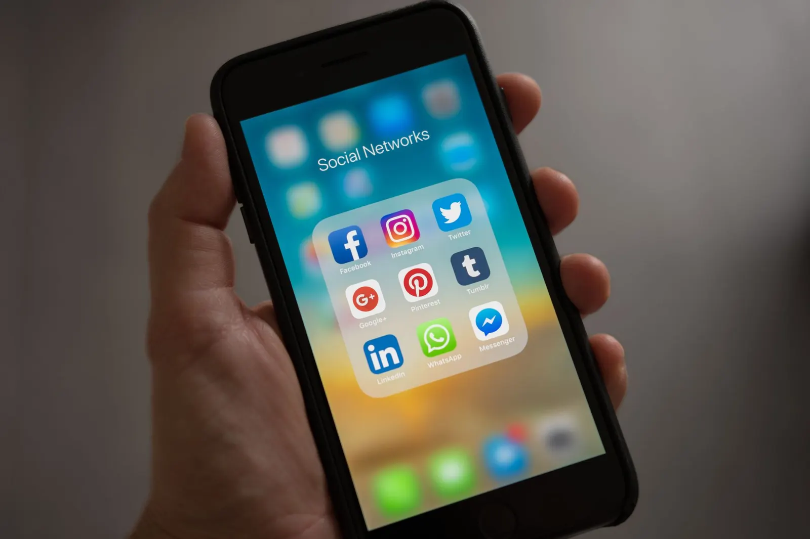 Hand hält ein Smartphone mit einem Ordner voller Social-Media-Apps