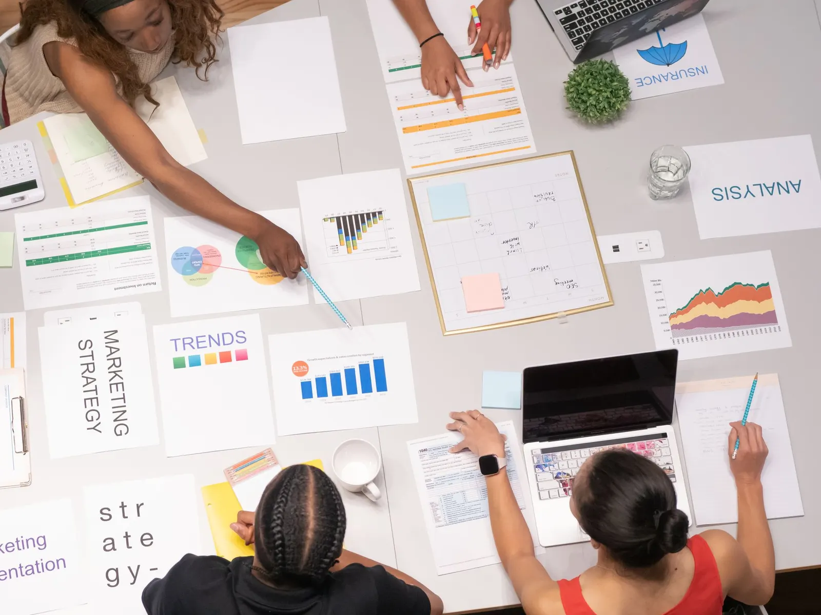 Team plant Online-Marketing mit Diagrammen, Notizen und Laptop auf einem Tisch